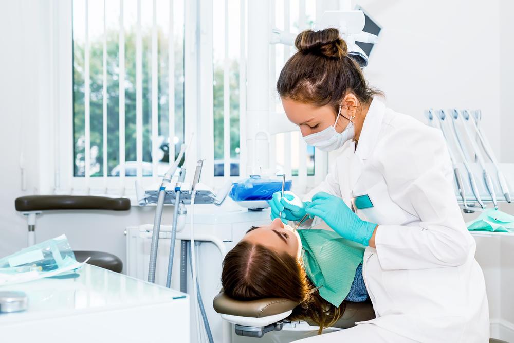 Female,Dentist,Checking,Up,Patient,Teeth,With,Braces,At,Dental