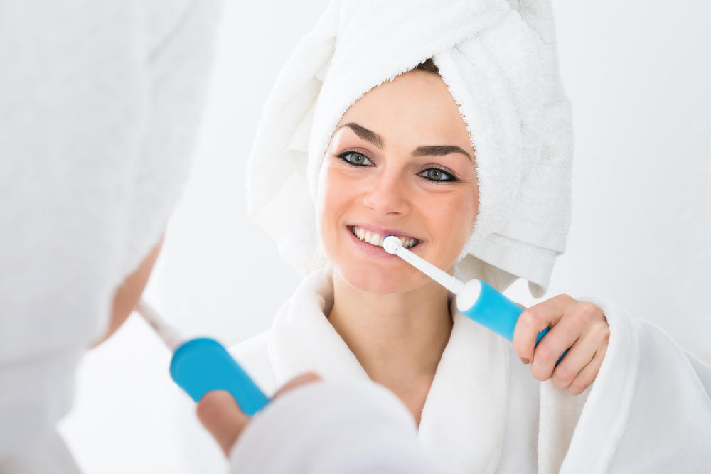 Close-up,Of,A,Woman,In,Bathrobe,Brushing,Teeth