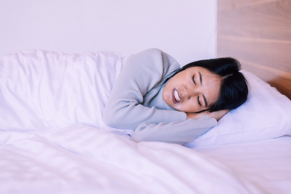 Woman grinding teeth while sleeping - 6 Ways to Stop Grinding Your Teeth